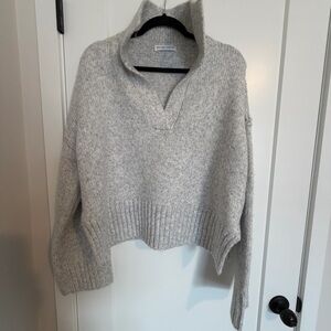 Neutral Long sleeves, collared V-neckline, and an oversized fit with side slits.